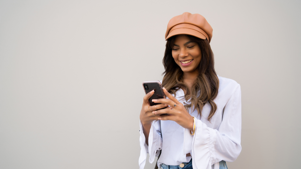 woman smiling looking at her phone in her hands.